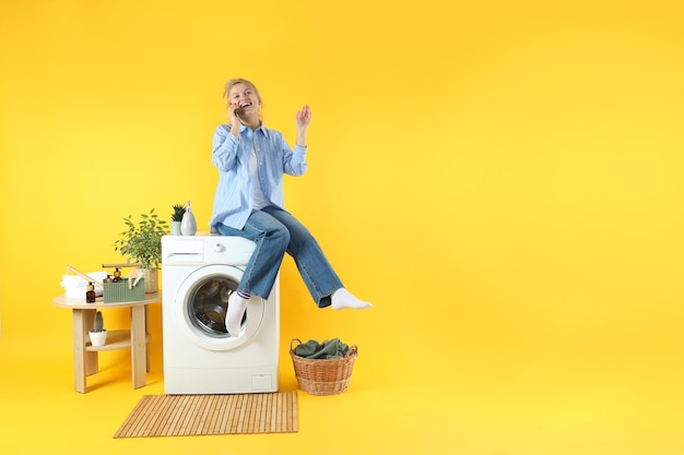 Konzept der Hausarbeit mit Waschmaschine und Mädchen auf gelbem Hintergrund