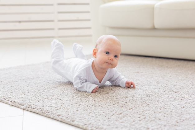 Konzept der Kindheit, des Babys und der Menschen - kleiner Junge oder Mädchen, die zu Hause auf dem Boden krabbeln.