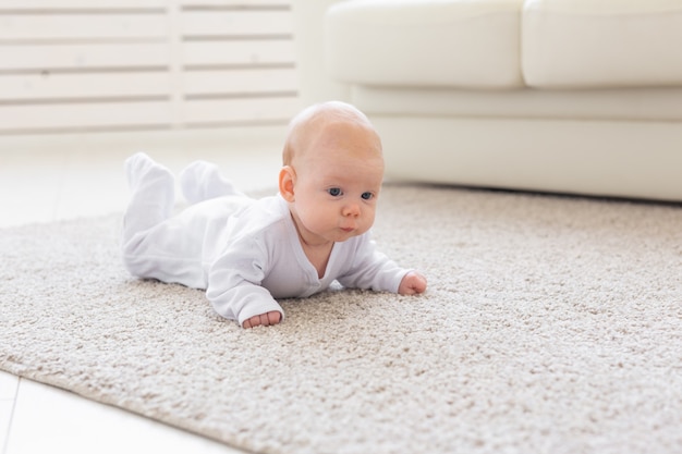 Konzept der Kindheit, des Säuglings und der Menschen - Babymädchen, das lernt, auf dem Boden zu krabbeln