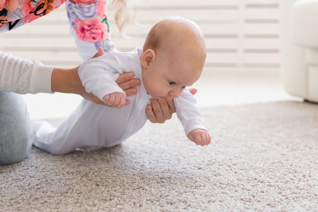 Konzept der Kindheit, des Säuglings und der Menschen - Babymädchen, das lernt, auf dem Boden zu krabbeln