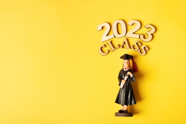 Konzept der Klasse 2023 Holznummer 2023 mit graduierter Statuette auf farbigem Hintergrund