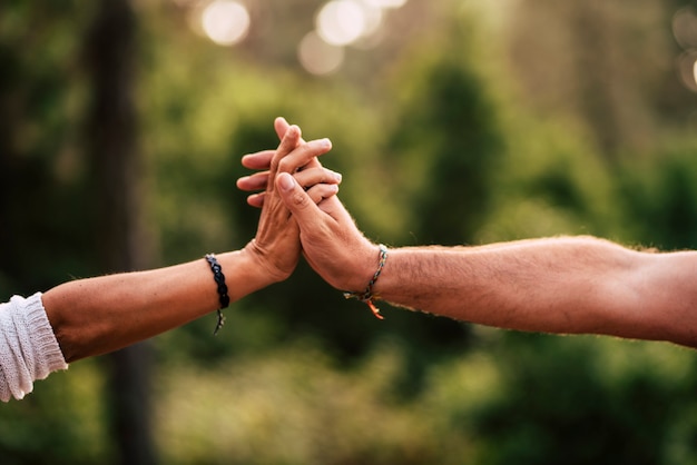 Konzept der Liebe und Beziehung für erwachsene kaukasische Menschen mit Nahaufnahme auf ein Paar Hände, die mit grünem Naturwald defokussiert halten und berühren