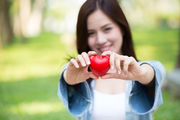 Konzept der Liebe zusammen geben: Rotes Herz des netten Asiatingriffs für das Lieben teilen reizend