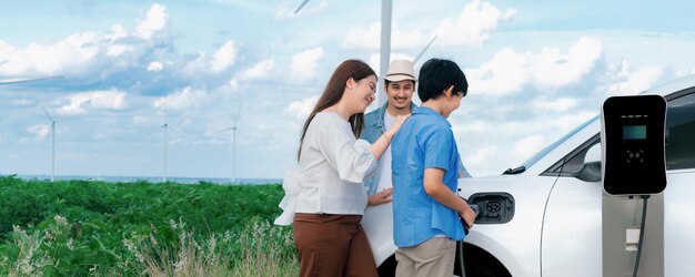 Konzept der progressiven glücklichen Familie im Windpark mit Elektrofahrzeug