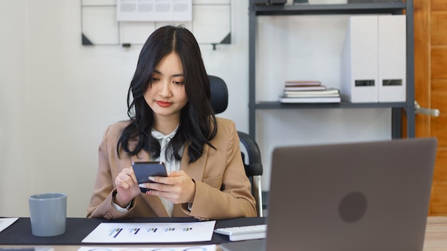 Konzept der Sekretärin Sekretärin liest Geschäftsberichte und chattet auf dem Smartphone im Büro