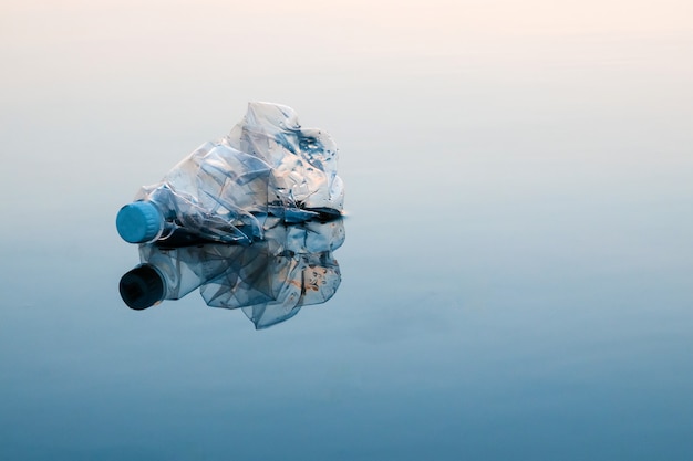 Konzept der Verschmutzung, kreativ. Eine Plastikflasche, die in den Ozean schwimmt