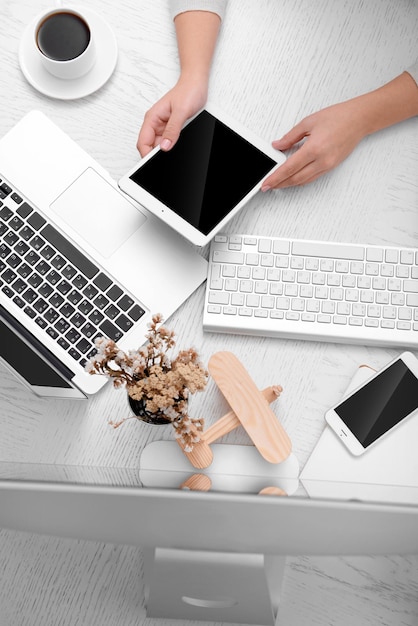 Konzept der Verwendung von Elektronik Geschäftsfrau arbeitet im Büro Nahaufnahme Computer Laptop Tablet Tasse Kaffee und andere Dinge auf dem Tisch Draufsicht