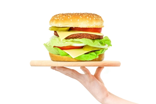 Konzept der weiblichen Hand des Lebensmittelservices, die ein Holzbrett mit einem großen Hamburger auf einem weißen Hintergrund hält, gemischtxA