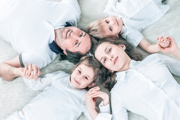 Konzept des Familienglücks glückliche Familie, die am Sonntag auf dem Teppich entspannt
