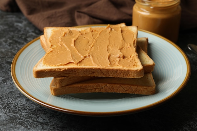 Konzept des Frühstücks mit Erdnussbutter-Toast auf schwarzem rauchigem Tisch