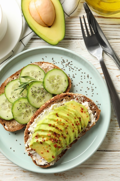 Konzept des Frühstücks mit Toast mit Avocado und Gurke auf Holztisch