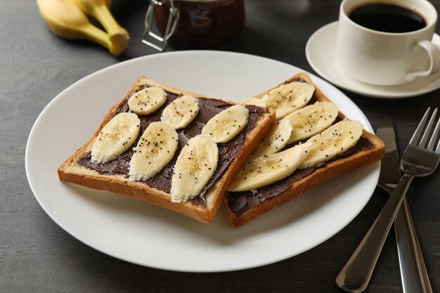 Konzept des Frühstücks mit Toast mit Banane auf hölzernem Hintergrund