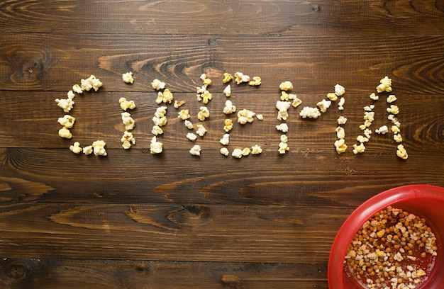 Konzept des Kinos. Word Cinema buchstabiert mit Popcorn über Holzhintergrund