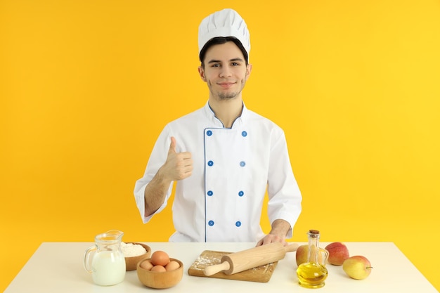 Konzept des Kochens junger männlicher Koch auf gelbem Hintergrund