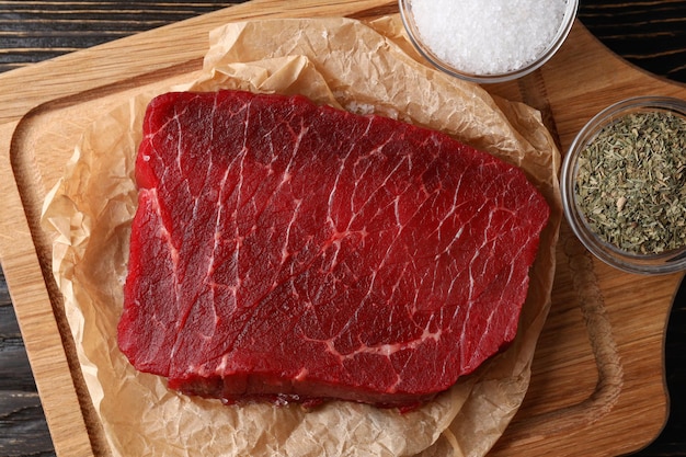 Konzept des Kochens mit rohem Steak auf Holzhintergrund