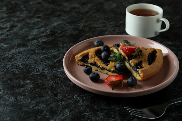 Konzept des köstlichen Essens mit Blaubeerkuchen auf schwarzem rauchigem Hintergrund