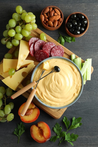 Konzept des köstlichen Essens mit Fondue auf dunklem Holztisch