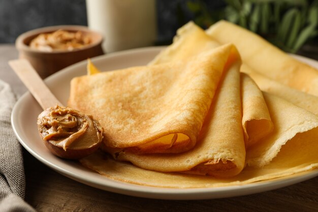 Konzept des köstlichen Frühstücks mit Crêpeteller mit Erdnussbutter auf Holzbrett