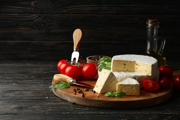 Konzept des leckeren Essens mit Camembert und Gewürzen auf hölzernem Hintergrund
