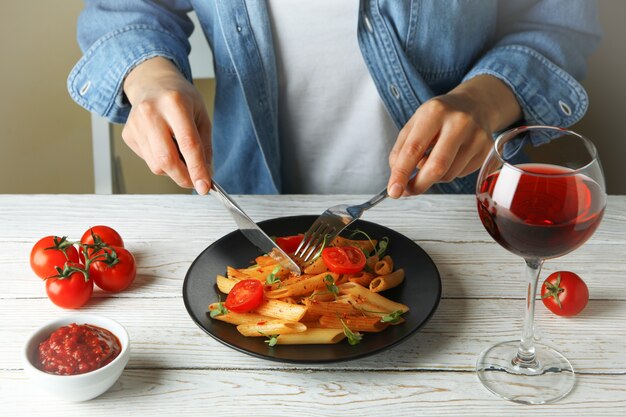 Konzept des leckeren Essens mit Frau isst Nudeln mit Tomatensauce auf weißem Holztisch