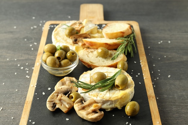 Konzept des leckeren Essens mit gegrilltem Camembert auf dunklem Holzhintergrund.