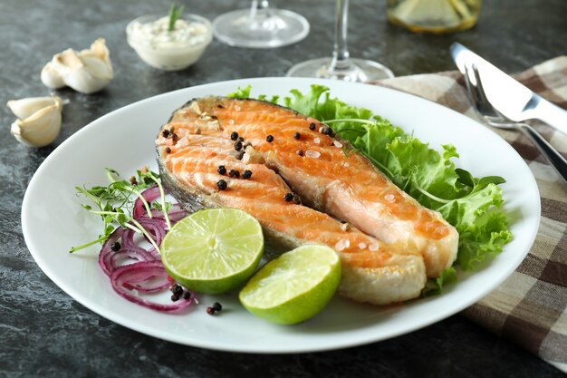 Foto konzept des leckeren essens mit gegrilltem lachs auf schwarzem rauchtisch