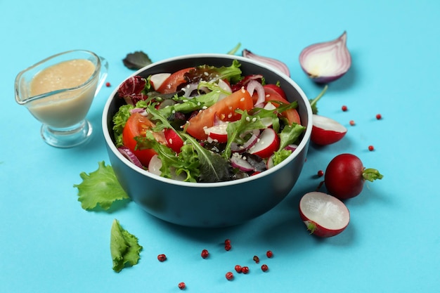 Konzept des leckeren Essens mit Gemüsesalat mit Tahini-Sauce auf blauem Hintergrund