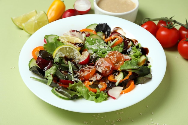 Konzept des leckeren Essens mit Gemüsesalat mit Tahini-Sauce auf grünem Hintergrund