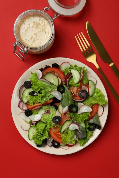 Konzept des leckeren Essens mit Gemüsesalat mit Tahini-Sauce auf rotem Hintergrund