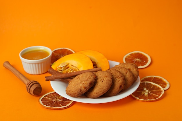 Konzept des leckeren Essens mit Kürbisplätzchen auf orangem Hintergrund.