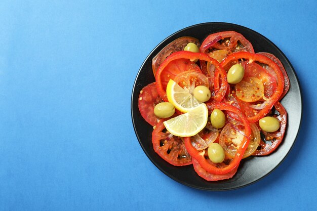 Konzept des leckeren Essens mit Tomatencarpaccio auf blauem Hintergrund