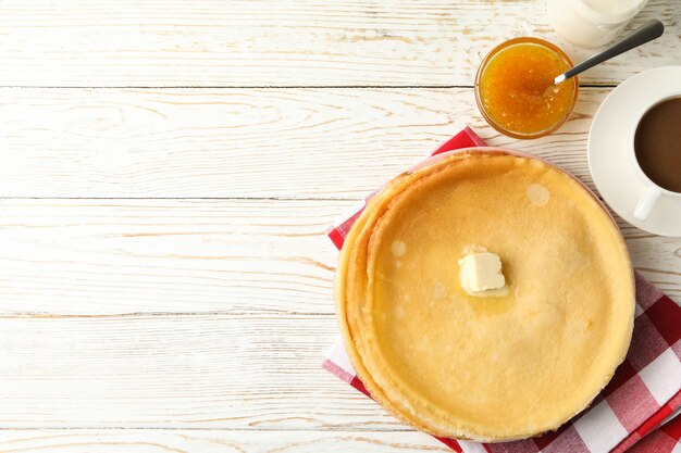 Konzept des leckeren Frühstücks mit dünnen Pfannkuchen auf weißem Holztisch