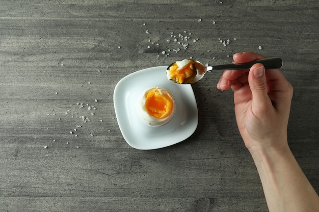 Konzept des leckeren Frühstücks mit gekochtem Ei auf grauem strukturiertem Hintergrund