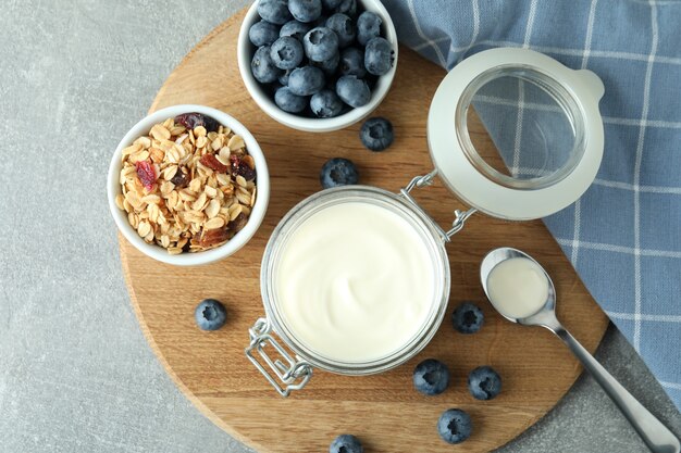 Konzept des leckeren Frühstücks mit Joghurt auf grauem strukturiertem Tisch