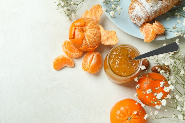 Konzept des leckeren Frühstücks mit Mandarinenmarmelade auf weißem strukturiertem Tisch