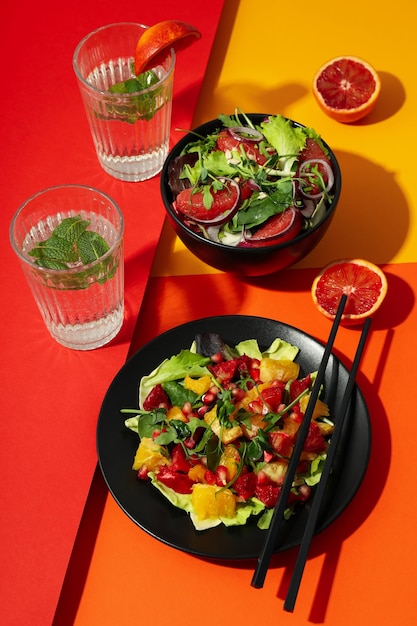 Konzept des leckeren Lebensmittelsalats mit roter Orange auf mehrfarbigem Hintergrund