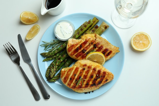 Konzept des leckeren Mittagessens mit gegrilltem Hähnchen und Spargel auf Weiß