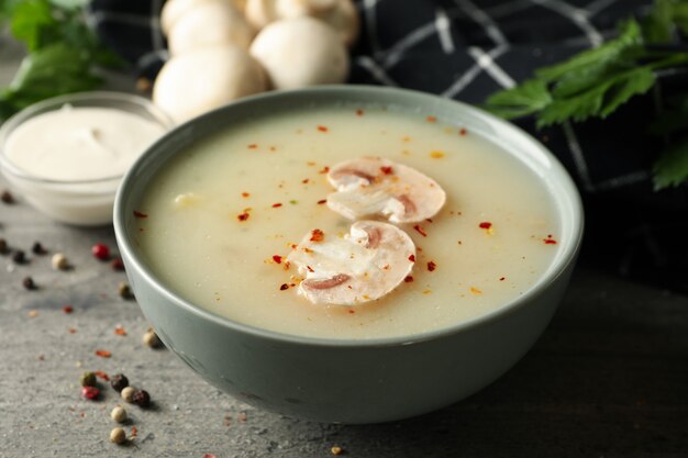 Konzept des leckeren Mittagessens mit Schüssel Pilzsuppe auf grau