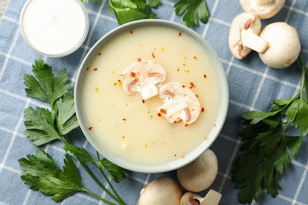 Konzept des leckeren Mittagessens mit Schüssel Pilzsuppe auf Serviettenhintergrund