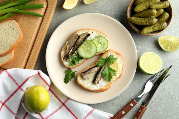 Konzept des leckeren Snacks mit Sandwiches mit Sprotten auf grauem strukturiertem Hintergrund
