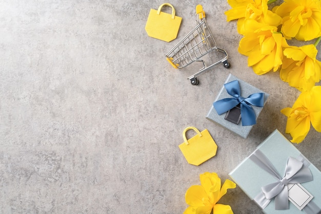 Konzept des Muttertags-Feiertagsgeschenk-Shopping-Grußdesigns mit gelbem Tulpenblumenstrauß auf grauem Hintergrund