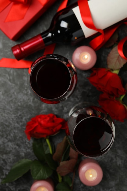 Konzept des Valentinstags mit Rosen und Wein auf schwarzem rauchigem Tisch