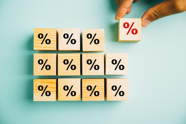 Foto konzept des zinssatzes und des finanzrankings. die hand eines geschäftsmannes platziert einen holzwürfelblock mit einem prozentsymbol, das die bedeutung der überwachung der zinssätze hervorhebt