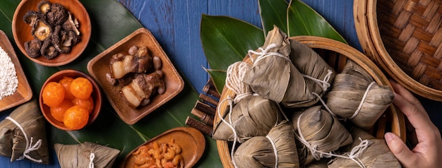 Konzept des Zongzi Dragon Boat Festival Reisknödel traditionelles chinesisches Essen auf blauem Holzhintergrund für das Duanwu Festival Top View Flat Lay Design Concept