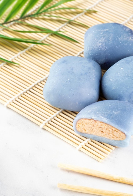 Konzept eines traditionellen japanischen Mochi mit einer Maki-Sudare-Matte und Stäbchen auf dem Tisch Ein japanischer Reiskuchen, der auf einer Holzmatte auf einer weißen Arbeitsplatte liegtAsiatisches Dessert Mochi-Eis Asiatische Küche