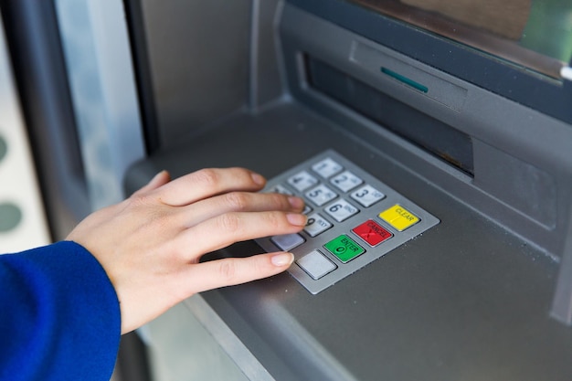 Konzept Finanzen, Technologie, Geld und Menschen - Nahaufnahme der Hand, die den PIN-Code am Geldautomaten eingibt