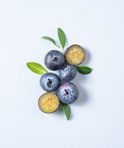 Konzept flach mit ein paar saftigen Blaubeeren mit grünen Blättern auf blauem Hintergrund. Draufsicht und Platzbild kopieren