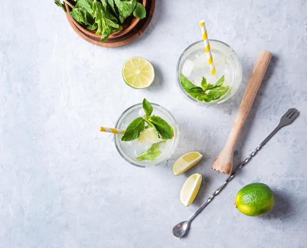 Konzept Flatlay-Mojito-Getränk Zwei Gläser Limettenlimonade mit Limettenscheiben-Juicer-Löffel und Minze auf Draufsicht des weißen Hintergrundes und Kopienraumbild