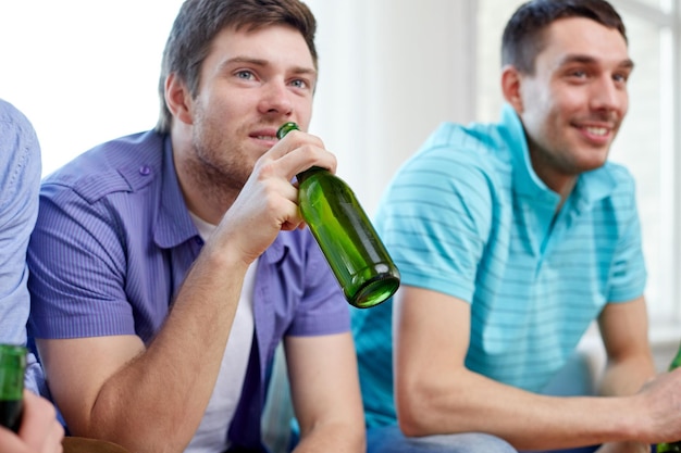 Foto konzept freundschaft, freizeit, menschen und alkohol - nahaufnahme glücklicher männlicher freunde, die zu hause bier trinken