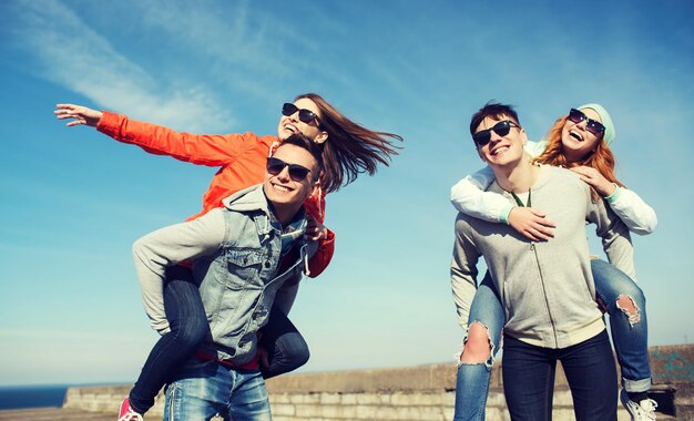 Konzept Freundschaft, Freizeit und Menschen - Gruppe glücklicher Teenager-Freunde mit Sonnenbrille, die sich im Freien amüsieren